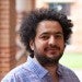 Professional headshot of Dr. Ali Siahkoohi in a blue plaid button-down shirt in front of brick background on Rice University campus.